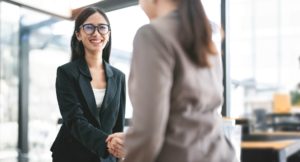 Two business women shaking hands and smiling